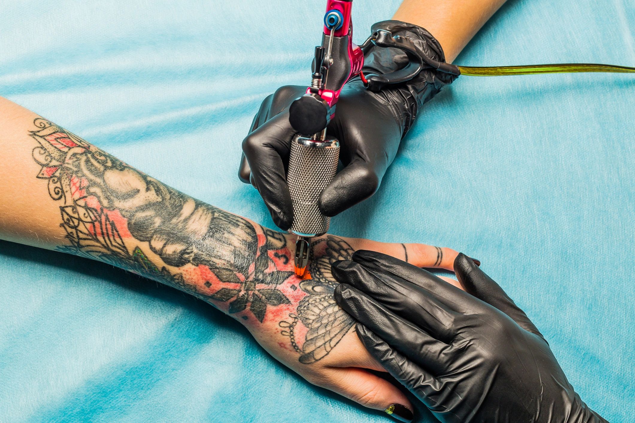 Close up tattoo artist demonstrates the process of tattooing.